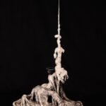a sculpture of a figure appearing to emerge out of a thick, batter-like substance, dark at the base with many layers of poetry text, gradually becoming lighter and less dense as you look up toward the top of the sculpture that is creamy white with no text at all; the figure is twisted and contorted as though tired and struggling and the arm is dramatically upstretched in a straight long, thin, antenna-like form with a tiny grasping hand at the top; the poem title Questions of "I" wraps clearly around the arm; layers of the thick batter drip down and peel back away from the antenna arm; the face is only a concave mirror facing upward like an eager, empty tray waiting to be filled